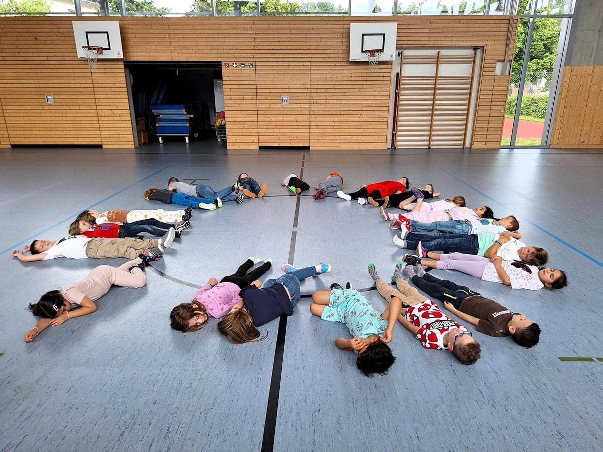 Im Turnraum bilden die Kinder liegend einen Kreis und entspannen sich